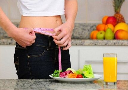 Una ragazza che sta perdendo peso mentre è a dieta misura la sua circonferenza vita